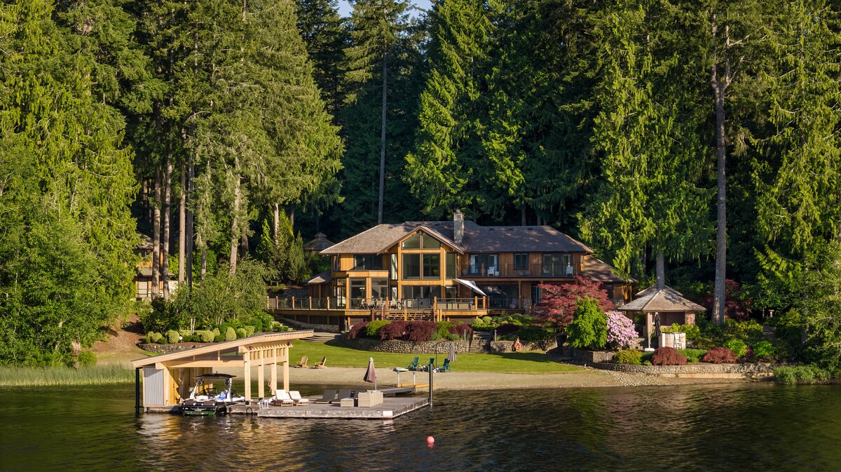 The main house, dock, and beach at Shawnigan Retreats viewed from the lake at golden hour