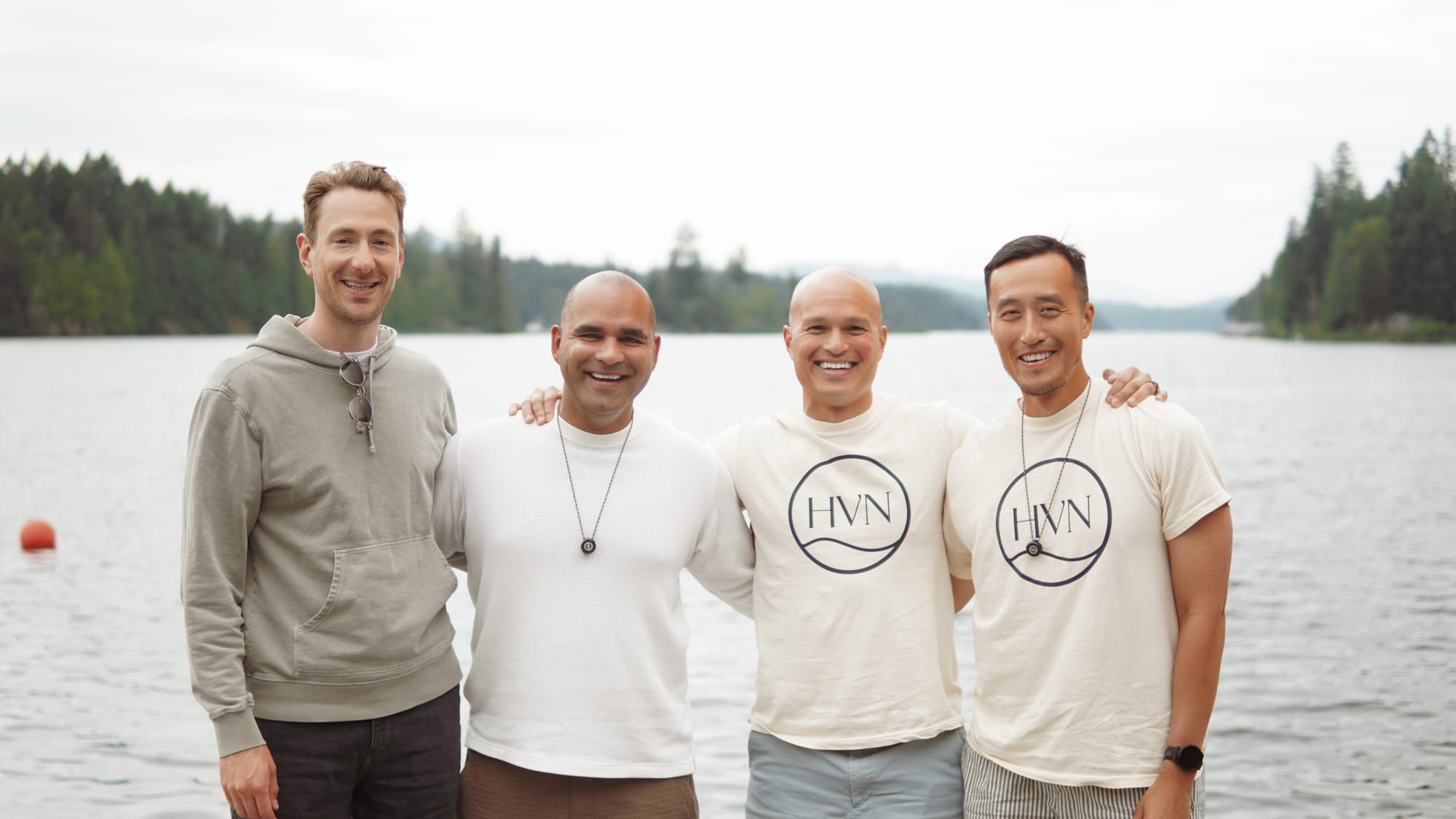 Four colleagues posing on the dock at golden hour, lake stretching behind them
